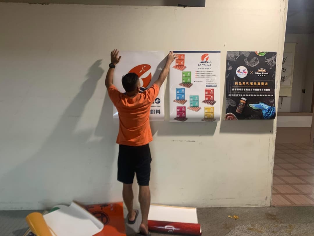 工作人員在牆上張貼比賽海報