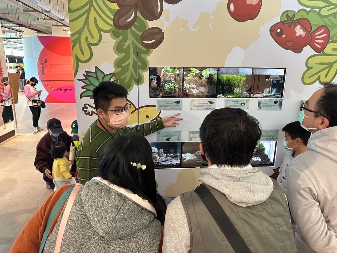 參觀者在展場聽解說、觀看牆上的螢幕