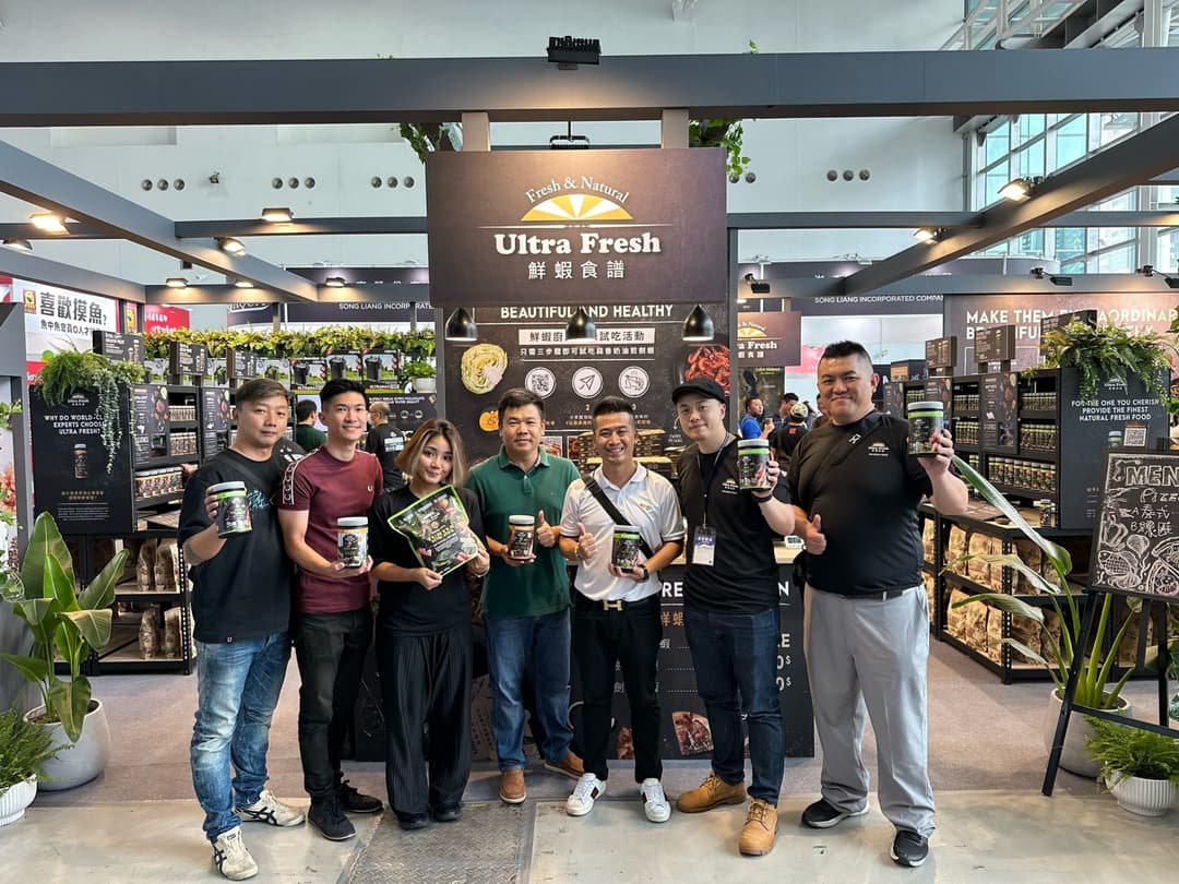 一群夥伴手持產品在展位前合影